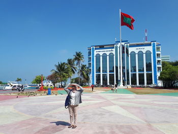 People standing at beach against clear blue sky