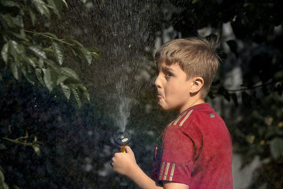 Side view of boy holding water