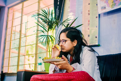 Portrait of smiling young woman sitting on sofa and eating food. women need quality food for diet.