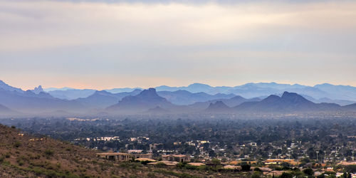 Aerial view of townscape and mountains against sky