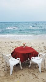 Deck chairs on beach against sky