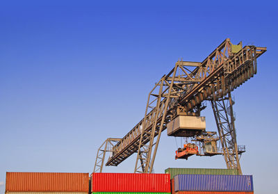 Low angle view of cargo containers and crane at harbor