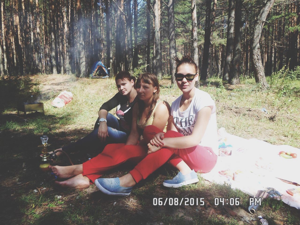 forest, tree, lifestyles, bonding, leisure activity, casual clothing, love, togetherness, young adult, young women, person, shadow, friendship, non-urban scene, woodland, rock - object, sitting, looking at camera, tree trunk, full length, tourist, front view, growth, nature, relaxation, vacations