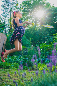 Side view full length of girl playing badminton at yard