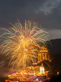 Firework display in city against sky at night