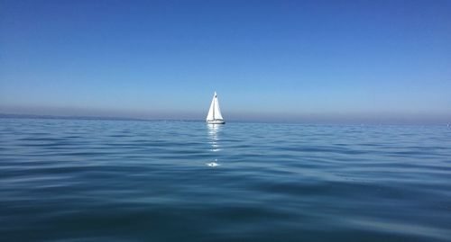 Sailboat sailing in sea against clear sky