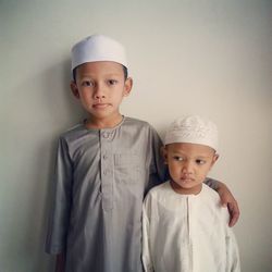 Boys in traditional clothing standing against wall