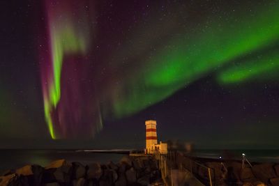 Scenic view of aurora borealis over sea against sky