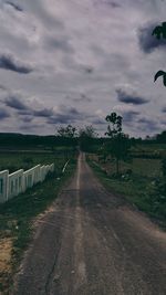 Road amidst field against sky