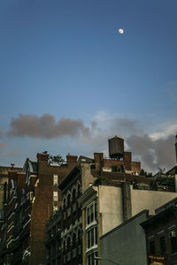 Low angle view of moon over residential buildings in city