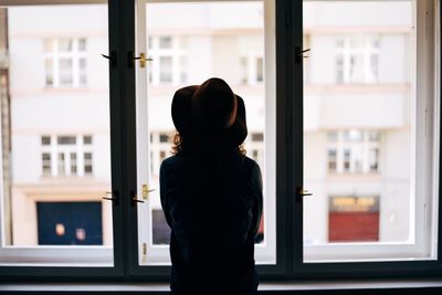 Rear view of woman standing by window