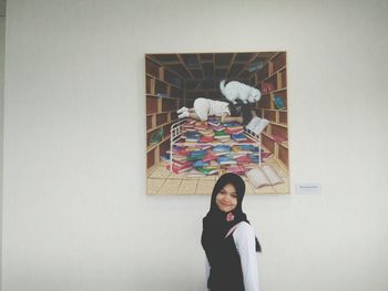 Portrait of young woman standing against wall