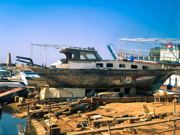 Fishing boats moored in water against clear blue sky