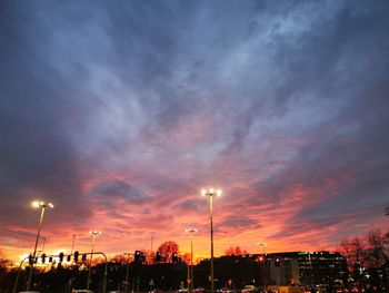 Low angle view of illuminated street lights against sky at sunset