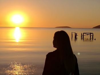 Woman looking at sea against sky during sunset