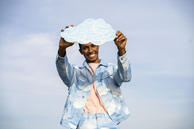 Man with umbrella standing against sky