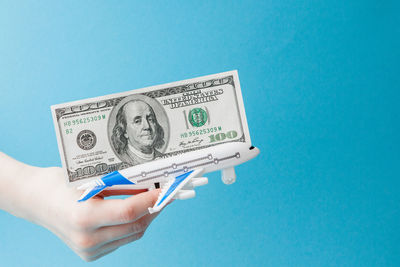 Close-up of hand holding paper against blue background