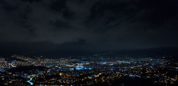 High angle view of illuminated city against sky at night