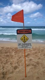 Information sign on beach against sky