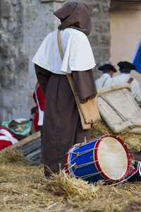 Person standing by drum on hay