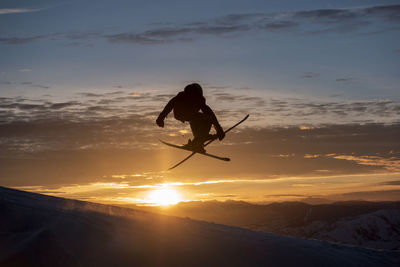 Silhouette man jumping against sky during sunset