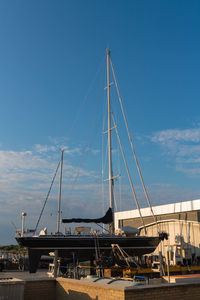 Sailboats moored at harbor against blue sky