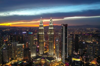 High angle view of city lit up against cloudy sky