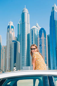 Woman looking at modern buildings in city against sky