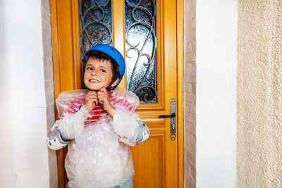 Portrait of young woman standing against window