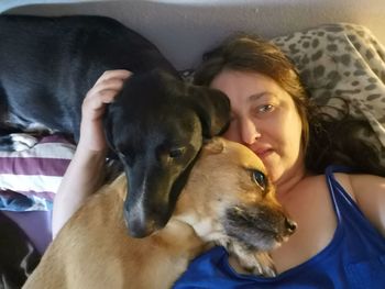 Portrait of young woman with dog on bed at home