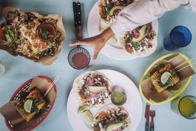 Directly above view of fresh tacos and snacks with drinks arranged on table at restaurant