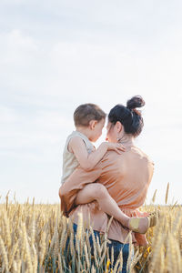 Side view of woman sitting on field against sky