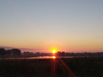 Scenic view of field against clear sky during sunset