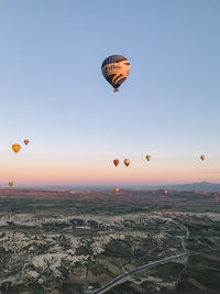 Hot air balloons flying over landscape against sky during sunset