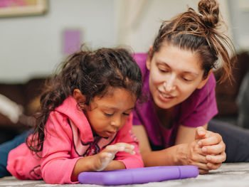 Mother and mixed race daughter at home having fun using a learning tablet computer 