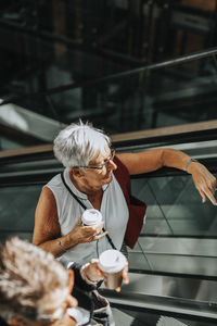 Senior woman standing on escalator