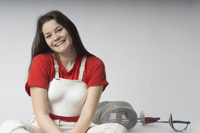 Portrait of smiling young woman sitting against white background