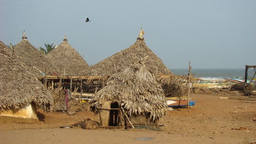 Thatched roof huts at sandy beach against clear sky