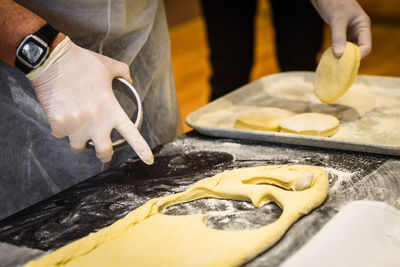 Midsection of man preparing cookies with dough at counter