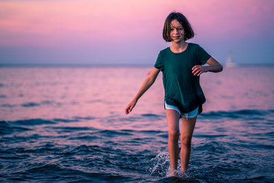 Full length of boy standing on beach against sky during sunset