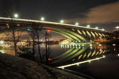 Illuminated bridge over river against sky at night