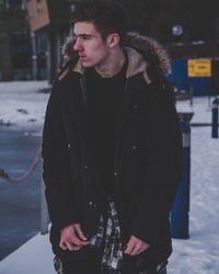 Thoughtful young man standing on snow field