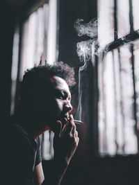 Man smoking cigarette by window