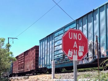 Road sign by train against blue sky