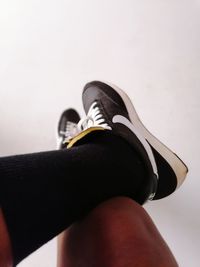 Low section of person wearing canvas shoes over white background