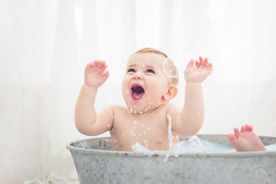 Shirtless baby girl playing with water in bathtub