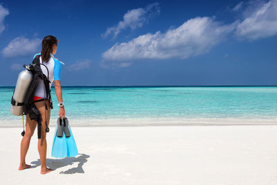 Rear view of woman with scuba diving equipment at beach