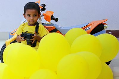 Boy with toy motorcycle by balloons