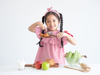 Portrait of smiling girl pointing at pretzel against white background