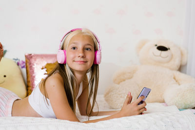 Teenager with headphones listens to music in bed, communicates on social networks in the morning